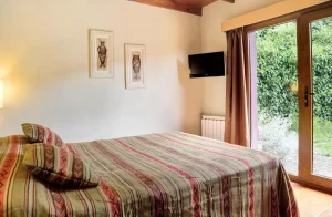 Cabañas La Caleta habitacion con cama doble y puerta hacia el jardin
